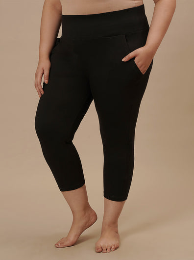 Plus-size woman in left side view wearing Black Plus Size Capri Pants with fitted silhouette and cropped length
