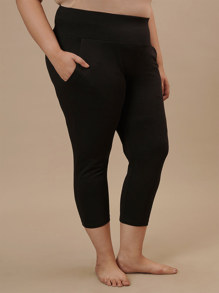 Plus-size woman in right side view wearing Black Plus Size Capri Pants with mid-rise waist and cropped leg design