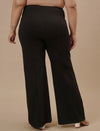 Plus-size woman in back view wearing Black Plus Size Flare Pants featuring flared leg and contoured fit