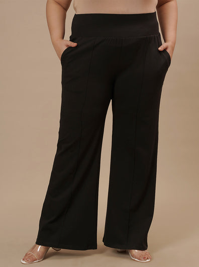 Plus-size woman in front view wearing Black Plus Size Flare Pants with clean front and wide-leg silhouette