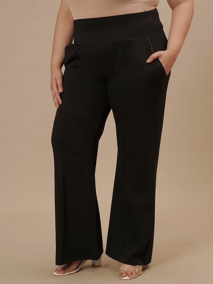 Plus-size woman in side angle view wearing Black Plus Size Flare Pants with flared hem and high-rise fit