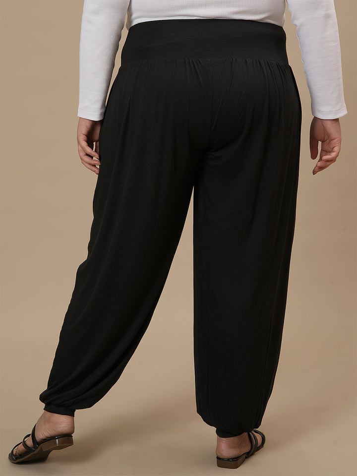 Plus-size woman in back view wearing Black Plus Size Harem Pants with loose fit and comfortable drape