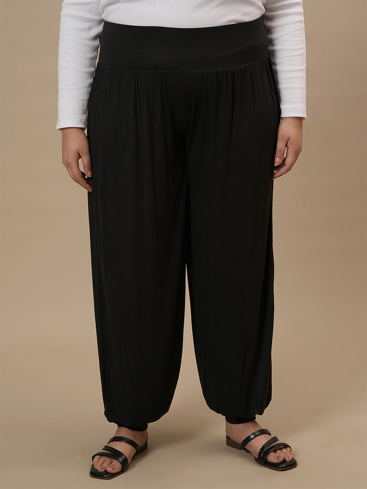 Plus-size woman in front view wearing Black Plus Size Harem Pants with roomy fit and cinched ankle hem