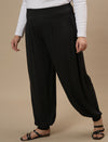 Plus-size woman in side view wearing Black Plus Size Harem Pants with relaxed fit and tapered ankle design