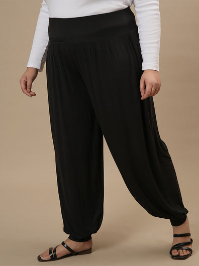 Plus-size woman in side view wearing Black Plus Size Harem Pants with relaxed fit and tapered ankle design
