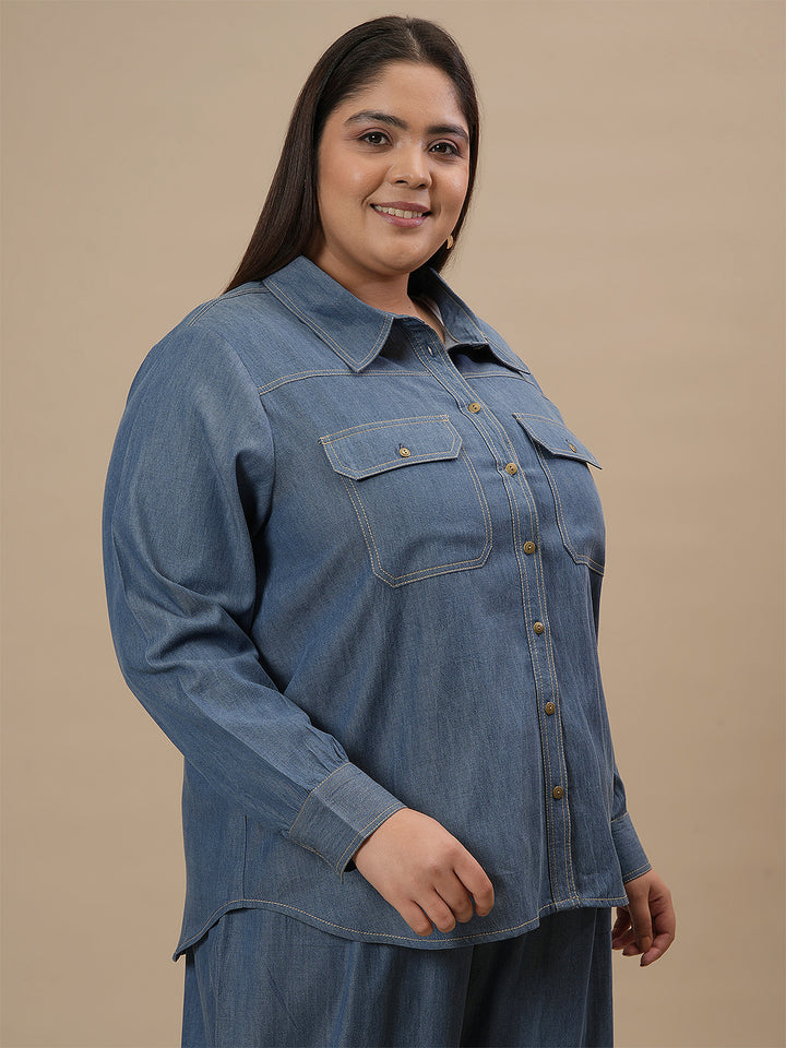 Plus-size woman in right side view wearing Blue Plus Size Denim Shirt with button-down front and relaxed fit