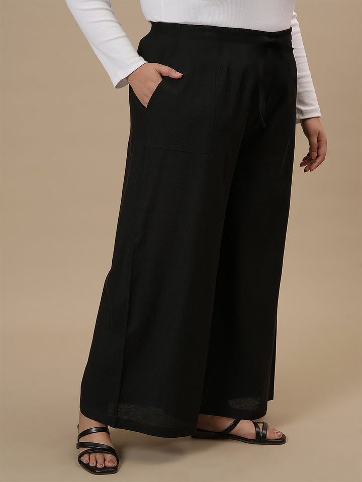 Plus-size woman in front right angle view wearing Black Plus Size Linen Palazzo Pants with flowy wide-leg design