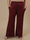 Plus-size woman posing with hands in pockets wearing Red Plus Size Flare Pants with high waist and flared hem